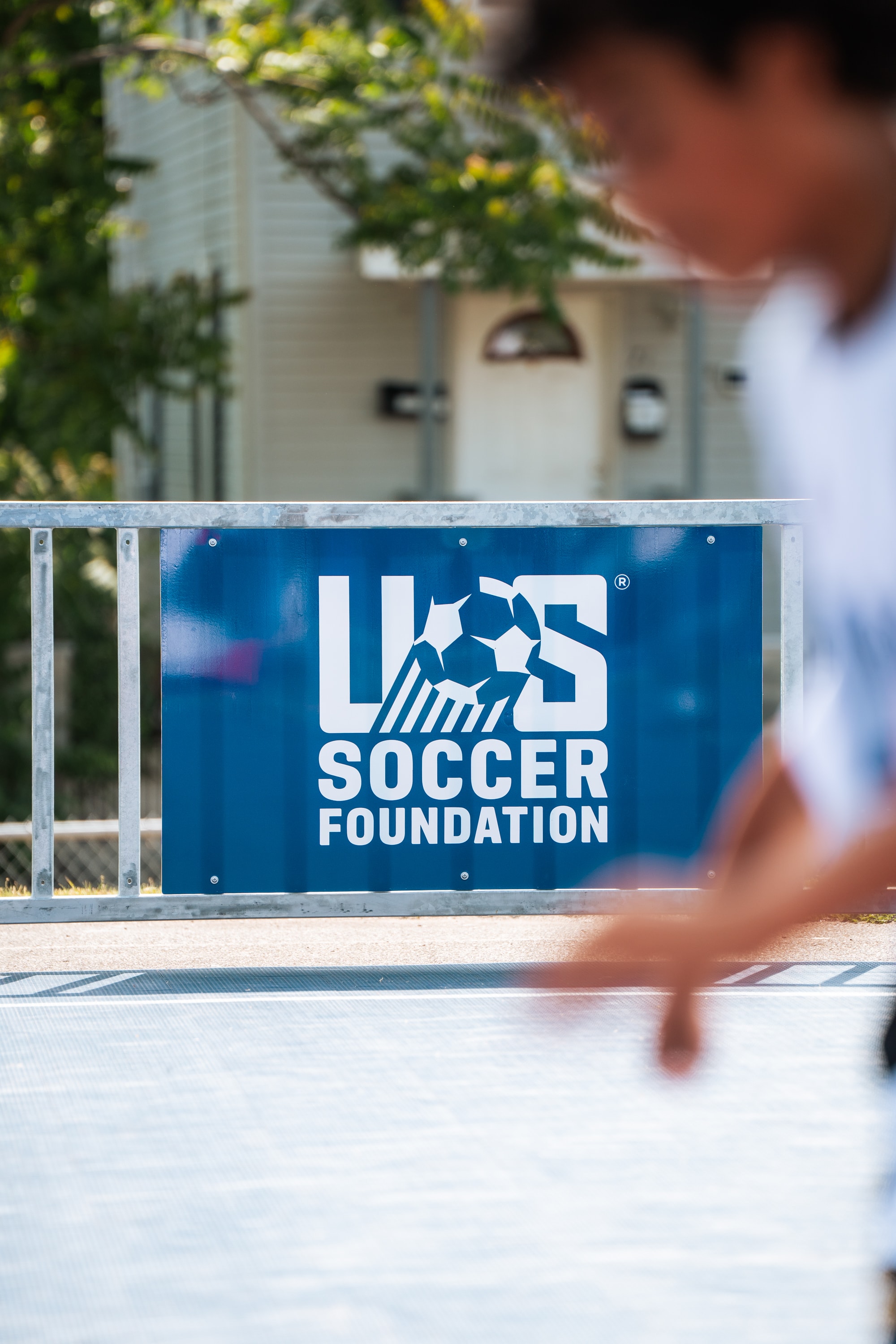 Player sprinting with US Soccer Foundation banner at Mulberry Park